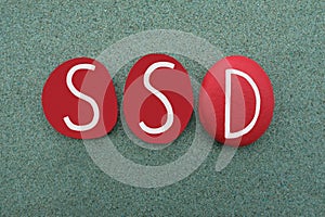 SSD, Shared Delusional Disorder, logo type composed with red colored stone letters over green sand