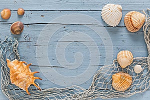 Sseashells and fishing net on blue wooden background