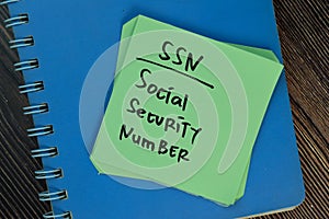 SSN - Social Security Number write on sticky notes isolated on Wooden Table photo