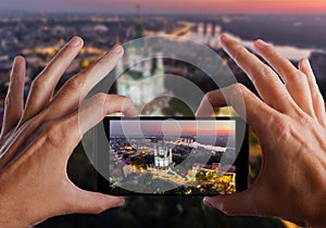 Travel concept. Hands making photo of St. Andrew`s Church Kiev Ukraine. Cityscape from a height.