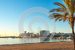 St Antoni de Portmany, Ibiza, Balearic Islands, Spain. Calm water along boardwalk & beach in warm, late day sunlight.