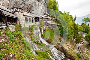 St. Beatus Cave and waterfalls above Thunersee, Sundlauenen, Switzerland. Falls are running down the mountain with a green grass
