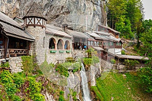 St. Beatus Cave and waterfalls above Thunersee, Sundlauenen, Switzerland. Falls are running down the mountain with a green grass