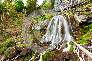 St. Beatus Cave and waterfalls above Thunersee, Sundlauenen, Switzerland. Falls are running down the mountain with a green grass