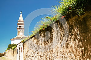 St. George`s Parish Church tower with flowers in Piran, Slovenia