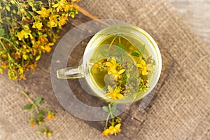St. John's wort tea is a therapeutic healthy drink A cup on a wooden background A bouquet of St. John's wort on