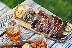 St louis style bbq ribs with collard greens and mac & cheese outside on picnic table during sunny summer day