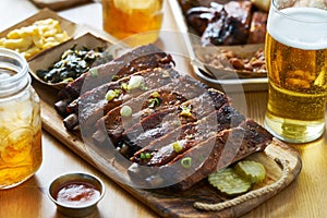 St louis style bbq ribs on table top with sweet tea, beer, collard greens and mac & cheese