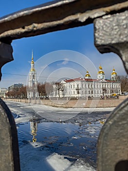St. Nicholas Naval Cathedral belltower through the forged lattice in a clear sunny day of spring, an ice drift on