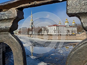 St. Nicholas Naval Cathedral belltower through the forged lattice in a clear sunny day of spring, an ice drift on