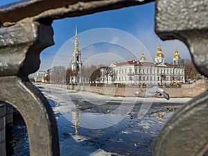 St. Nicholas Naval Cathedral belltower through the forged lattice in a clear sunny day of spring, an ice drift on