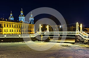 St. Nicholas naval Cathedral and night illumination of red guard bridge on the Griboyedov canal in winter in St