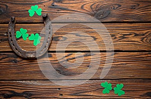 St. Patrick`s Day banner with rusty horseshoe and shamrocks on wooden background