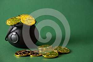 St. Patrick\'s day black pot with golden coins on green background