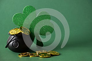 St. Patrick's day black pot with golden coins on green background.