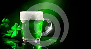 St. Patrick`s Day. Green beer pint over dark green background, decorated with shamrock leaves