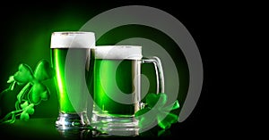 St. Patrick`s Day. Green beer pint over dark green background, decorated with shamrock leaves