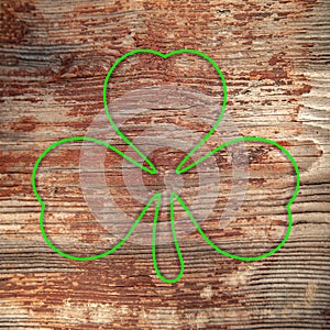 St. Patrick`s Day. Green shamrock outline is drawn on a shabby wooden surface. Three leaf clover