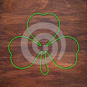 St. Patrick`s Day. Green shamrock outline is drawn on a wooden surface. Three leaf clover
