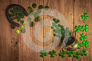 St.Patrick`s day holiday symbol. Shamrocks, horseshoe, coins and silver pot on vintage style wood background.