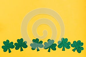 St. Patrick`s Day low border paper shamrocks on yellow background.