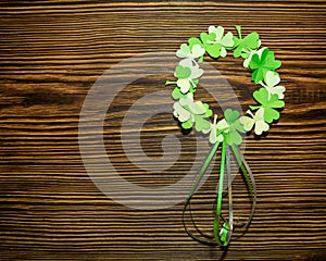 St. Patrick`s day. Paper wreath of clover leaves on a brown wooden background.