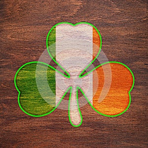 St. Patrick`s Day. Shamrock color of the Irish flag with a green border is drawn on a wooden surface. Three leaf clover