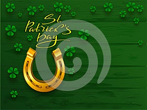 St. Patrick`s day text greeting card. Golden horseshoe and green leaf clover trefoil on green board background