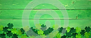 St Patricks Day banner with bottom border of shamrocks, overhead view over a green wood background