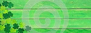 St Patricks Day banner with corner border of shamrocks, above view over a green wood background