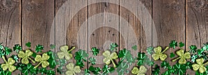 St Patricks Day bottom border of shiny shamrocks over a dark wood banner background