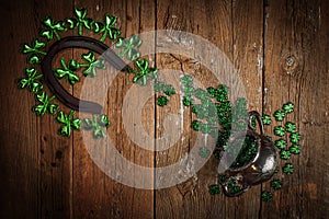 St. Patricks Day composition. Shamrocks, rusty horseshoe and silver pot on vintage style wood background.