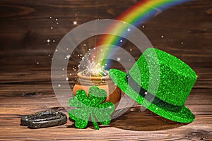 St Patricks day decoration with magic light rainbow pot full gold coins, horseshoe, green hat and shamrock on vintage wooden back