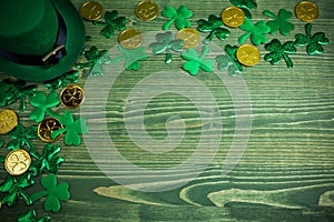 St Patricks Day frame of shamrocks, gold coins and leprechaun hat on green wood