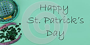 St Patricks day holiday celebration with Irish elf hat, horse shoe and clovers on a green paper background plus text