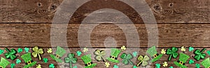 St Patricks Day shamrock and leprechaun hat bottom border over a rustic wood banner background