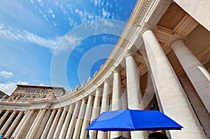 St. Peter's Basilica colonnades in Vatican City. Blue umbrella harmonizes with sky photo