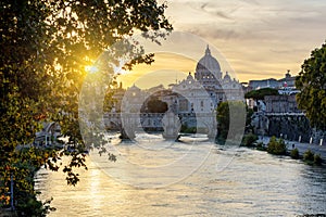 St. Peter`s basilica dome and St. Angel bridge over Tiber river at sunset in Rome, Italy