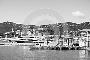 Luxury travel on boat, water transport. Yachts moored at sea pier on mountain landscape. Sea port and town on sunny blue