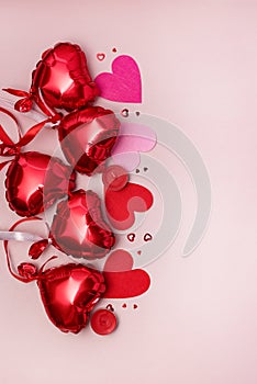 St Valentine\'s Day concept Top view photo of heart shaped shiny red balloons and confetti on pastel pink background