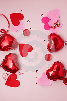 St Valentine\'s Day concept Top view photo of heart shaped shiny red balloons and confetti on pastel pink background