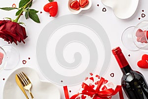 St Valentine`s Day concept. Top view photo of heart shaped tableware giftbox cutlery candies wine bottle glasses candles rose and