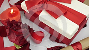 St. Valentine`s Day surprise presents. Gift box with red ribbon bow is rotating on white background. Decorated romantic background