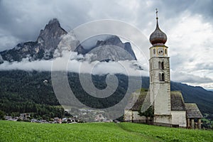 St Valentine's Church, Seis am Schlern, Italy. Schlern mountain with rainy clouds in background photo