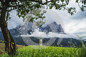 St Valentine's Church, Seis am Schlern, Italy. Schlern mountain with rainy clouds in background photo