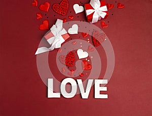 St. Valentines Day background word love, gifts and decorative hearts on red.