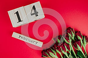 St. valentines day minimal concept on red background . Red roses and wooden caledar with 14 february on it