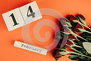 St. valentines day minimal concept on red background . Red roses and wooden caledar with 14 february on it