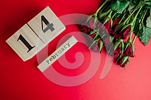 St. valentines day minimal concept on red background . Red roses and wooden caledar with 14 february on it