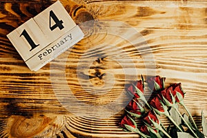 St. valentines day minimal concept on wooden background. Red roses and wooden caledar with 14 february on it